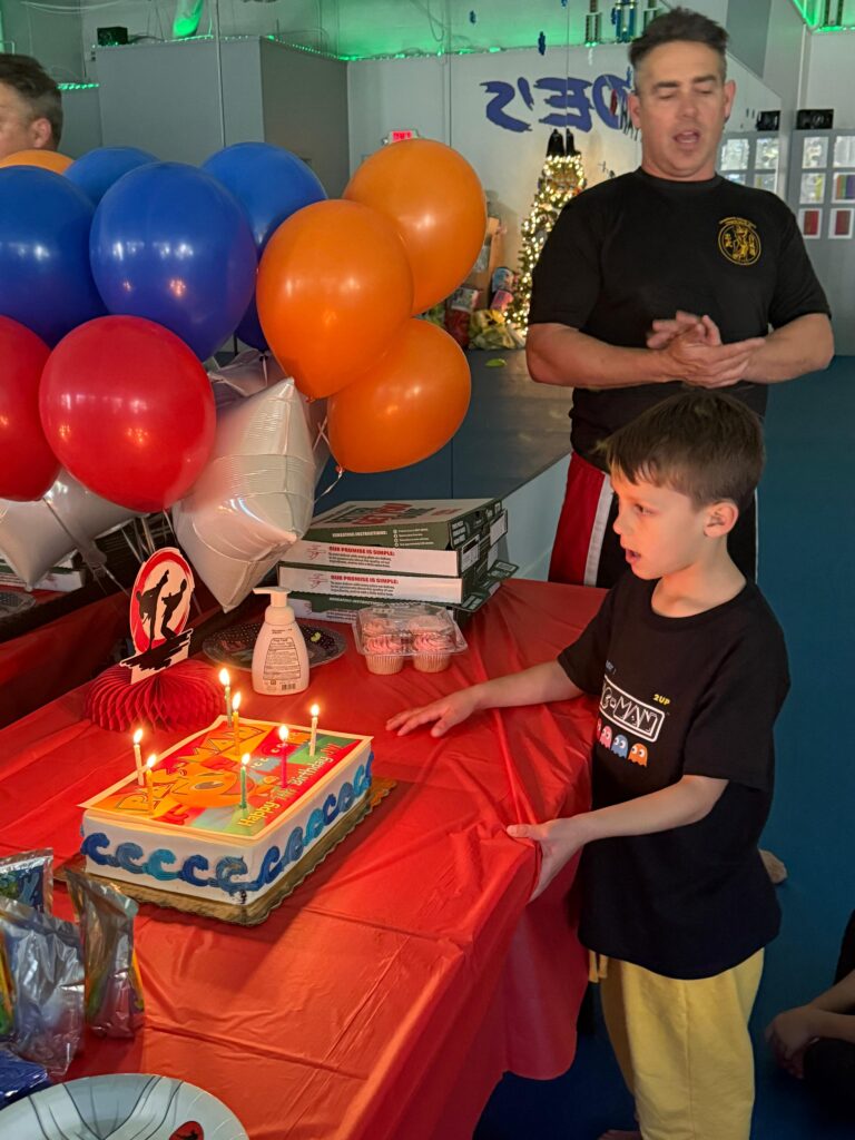 Group of children and adult holding balloons at karate birthday party on gym mat at Choe’s HapKiDo Cumming, GA.